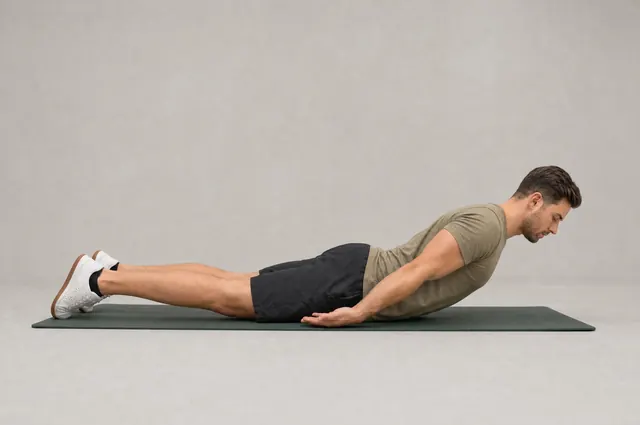 Prone hold: lying face down on a mat, chest lifted a few inches, arms along the sides.